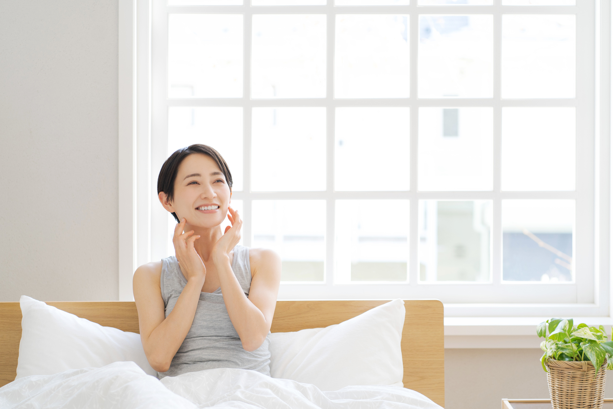 爽やかな白い部屋でベッドに入っている女性