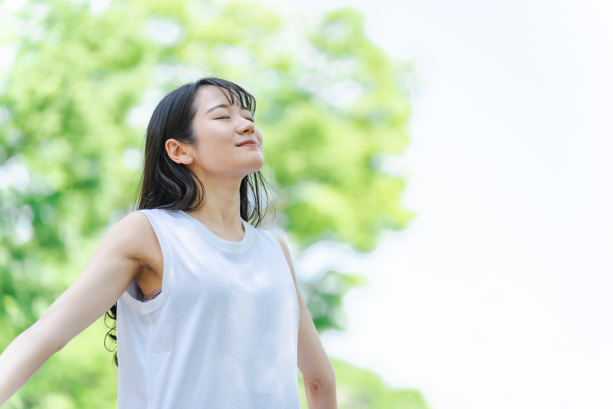 緑の中で深呼吸をする女性の写真