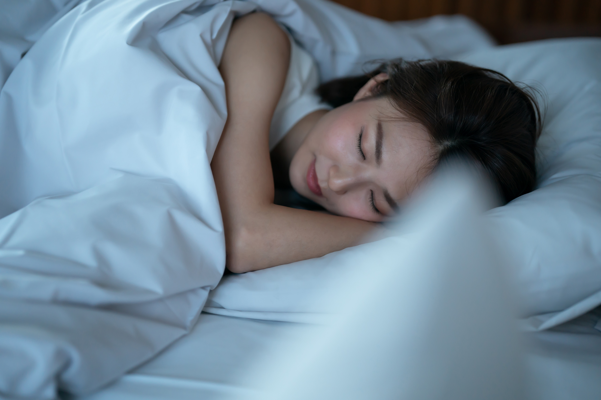 白いシーツに包まれて睡眠をとる女性