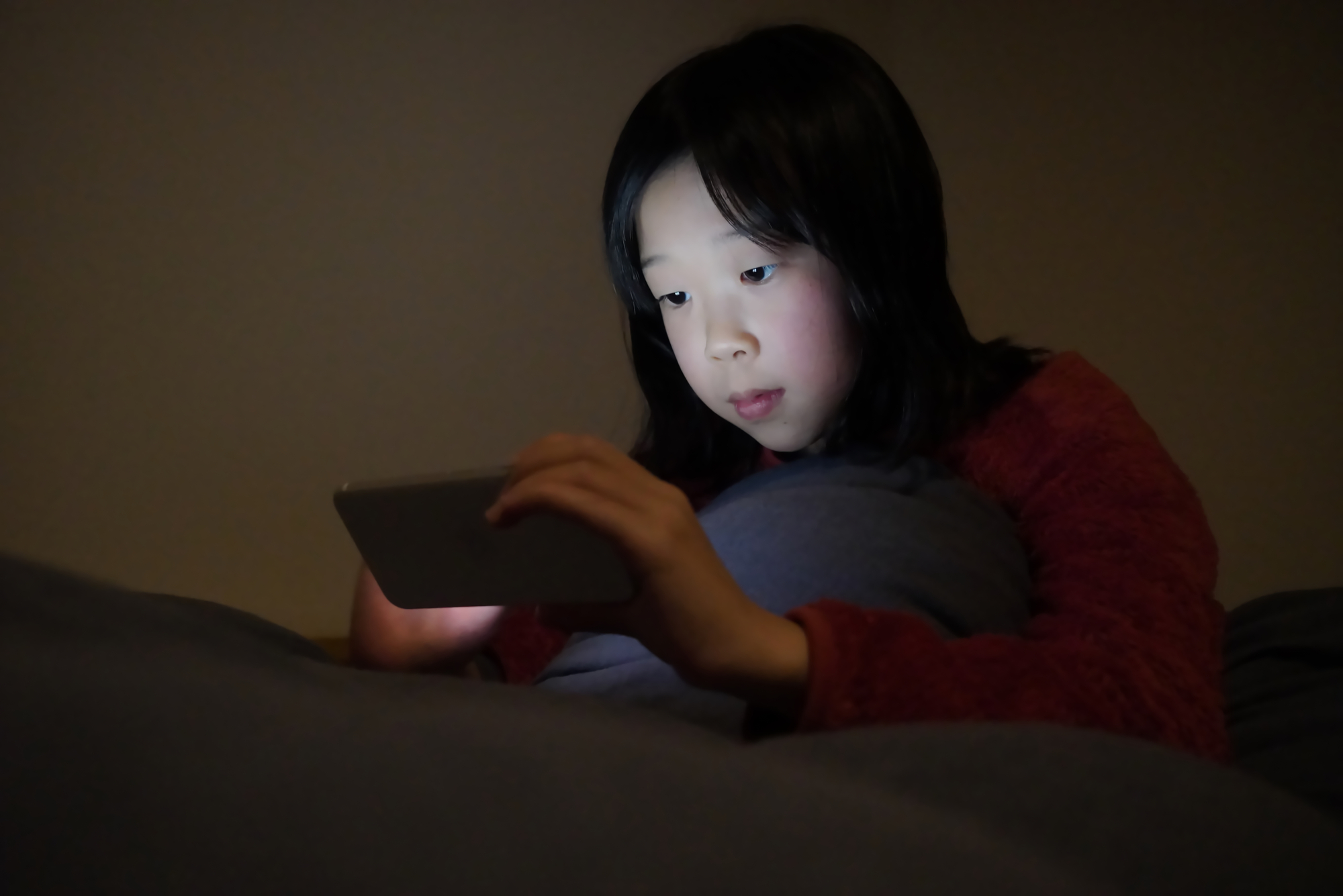 スマホを触り夜更かしをする子ども