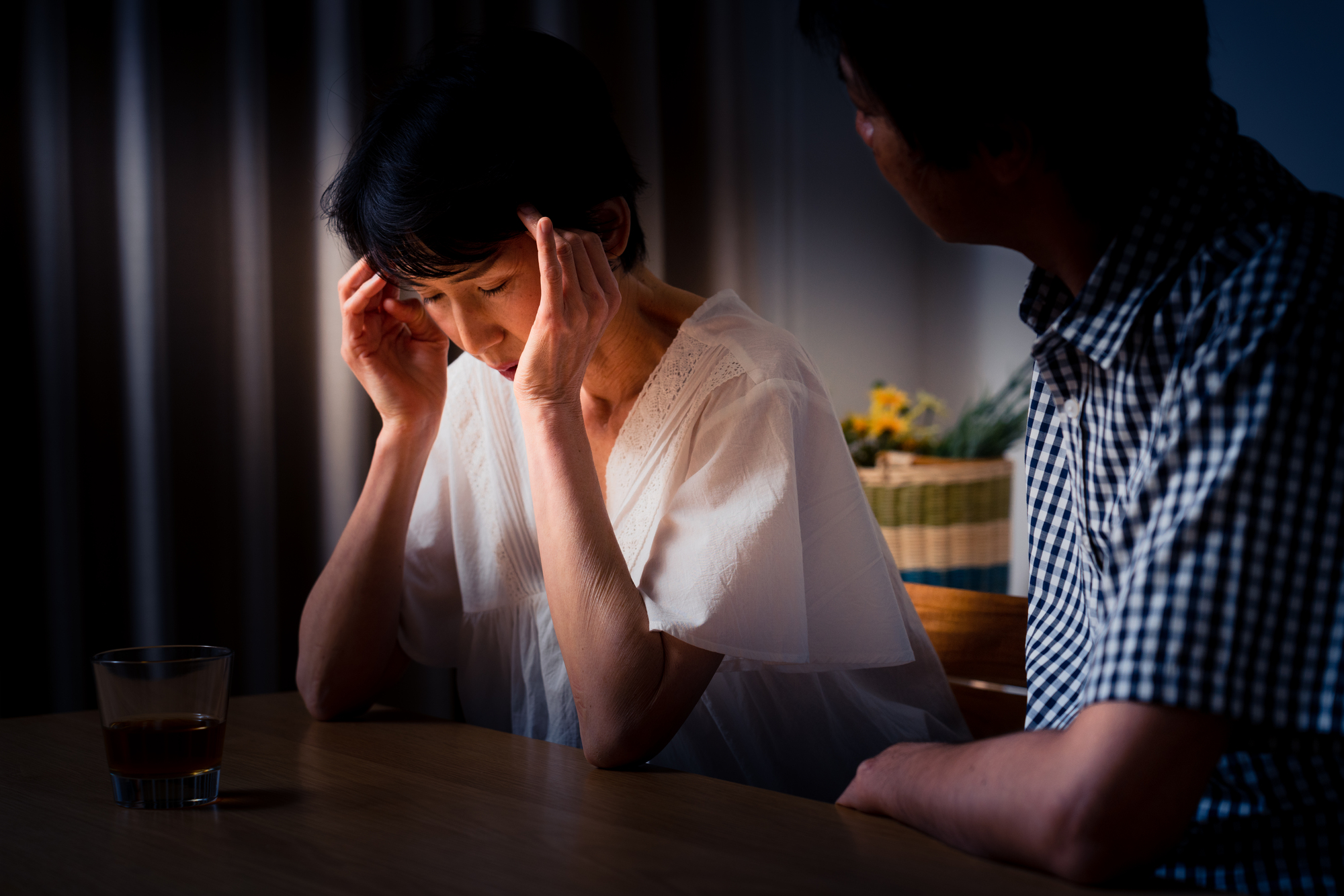 家でうなだれる女性と慰める男性