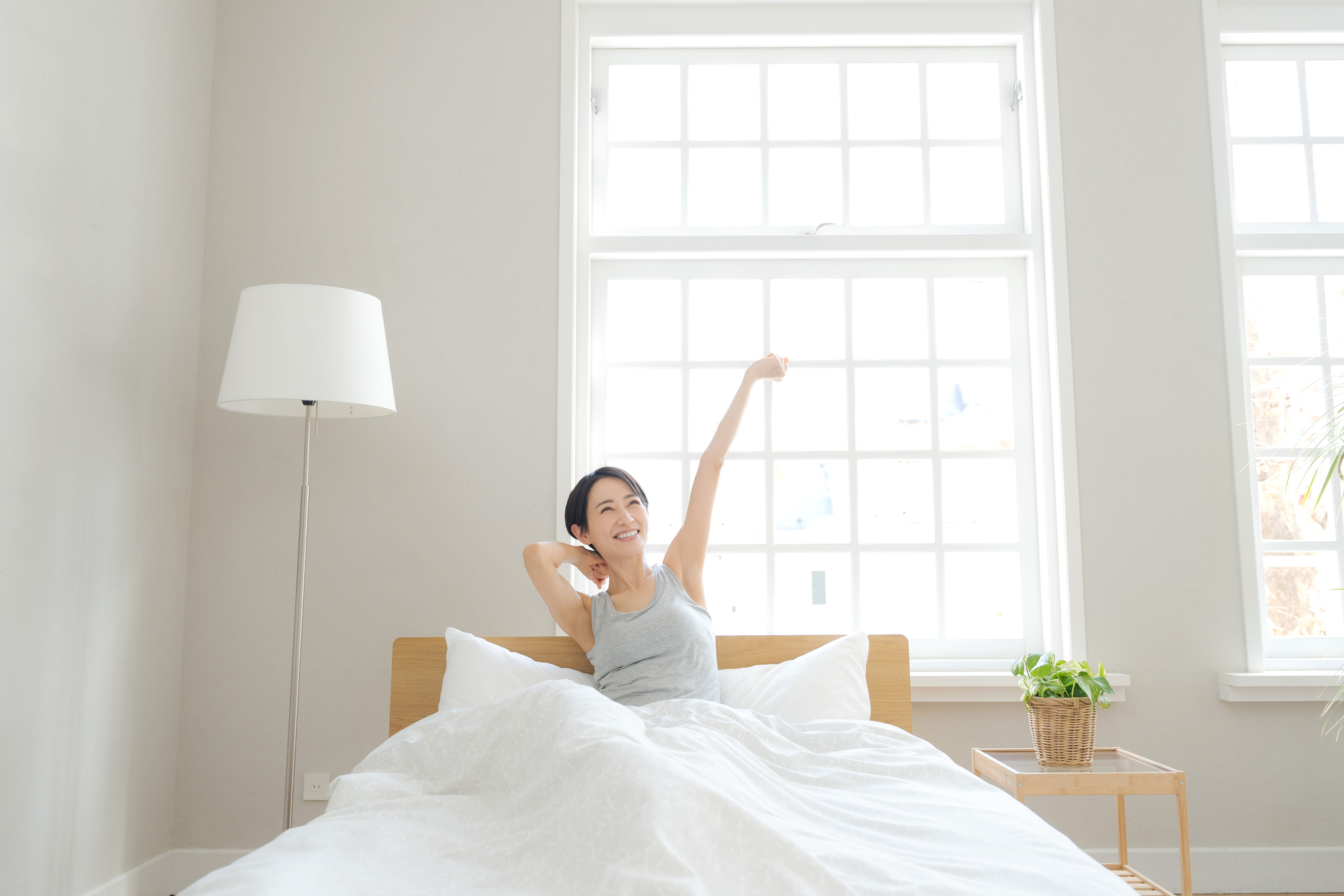 白を基調とした部屋、目覚める女性