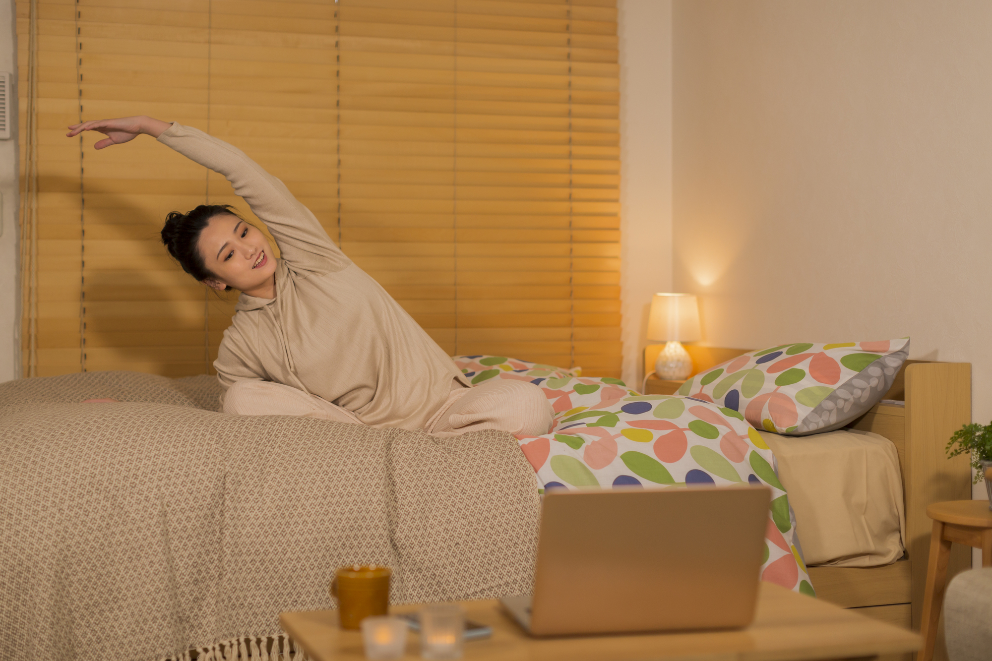 ベッドの上でストレッチをする若い女性