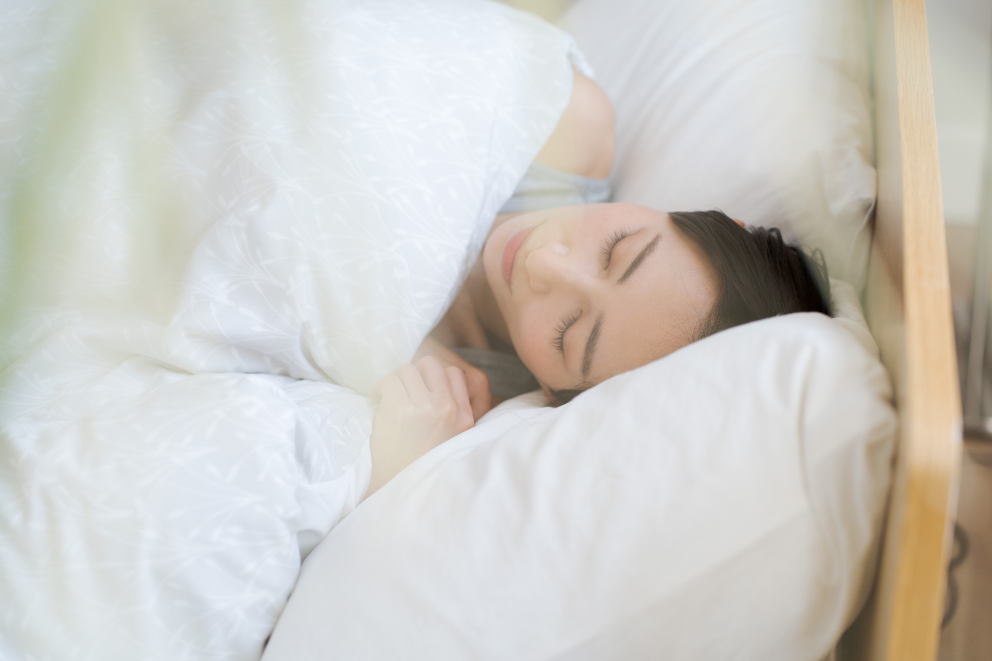 木のヘッドボードのあるベッドで睡眠中の女性