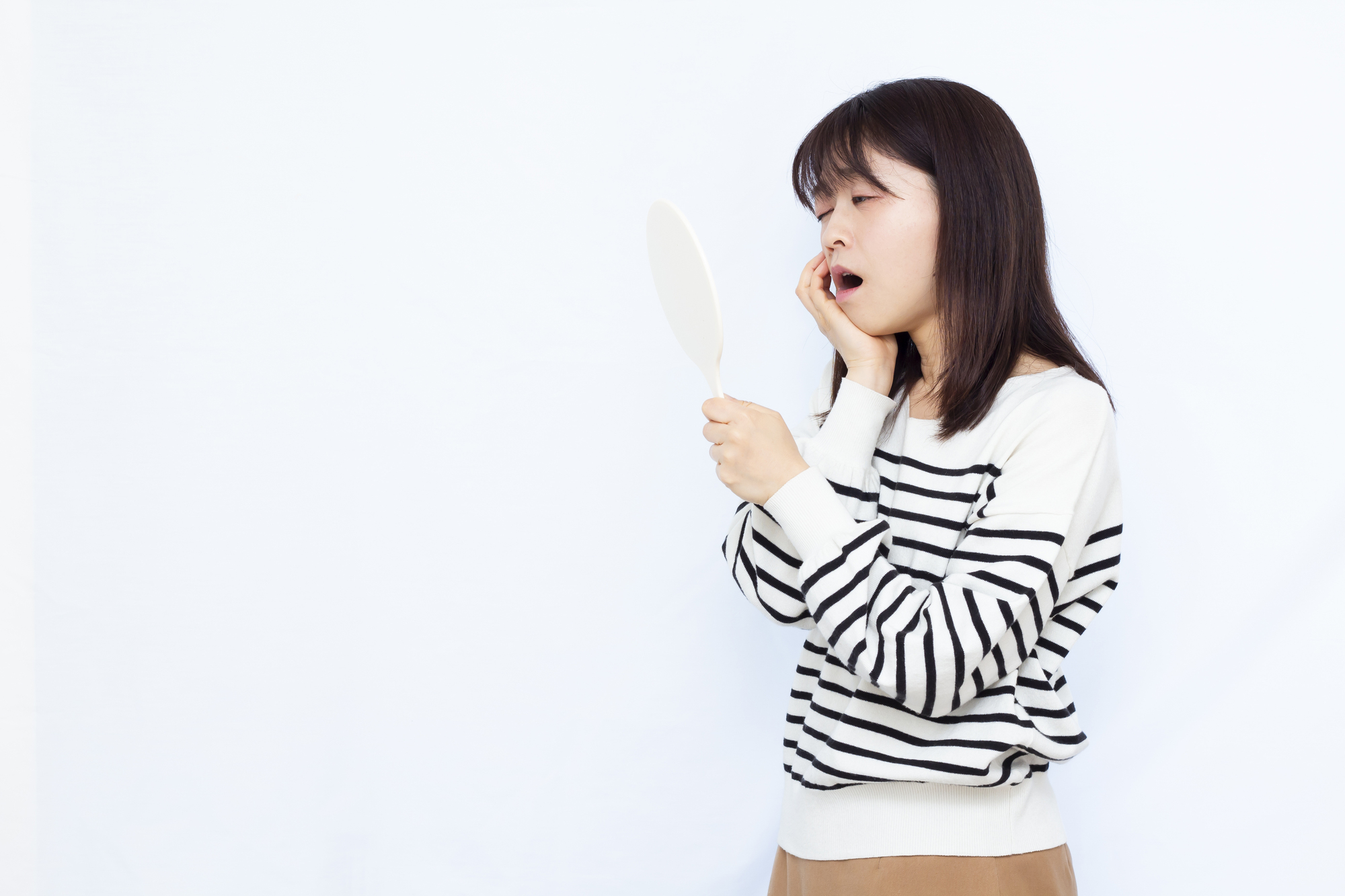 鏡を手に持ち、あごを気にする女性