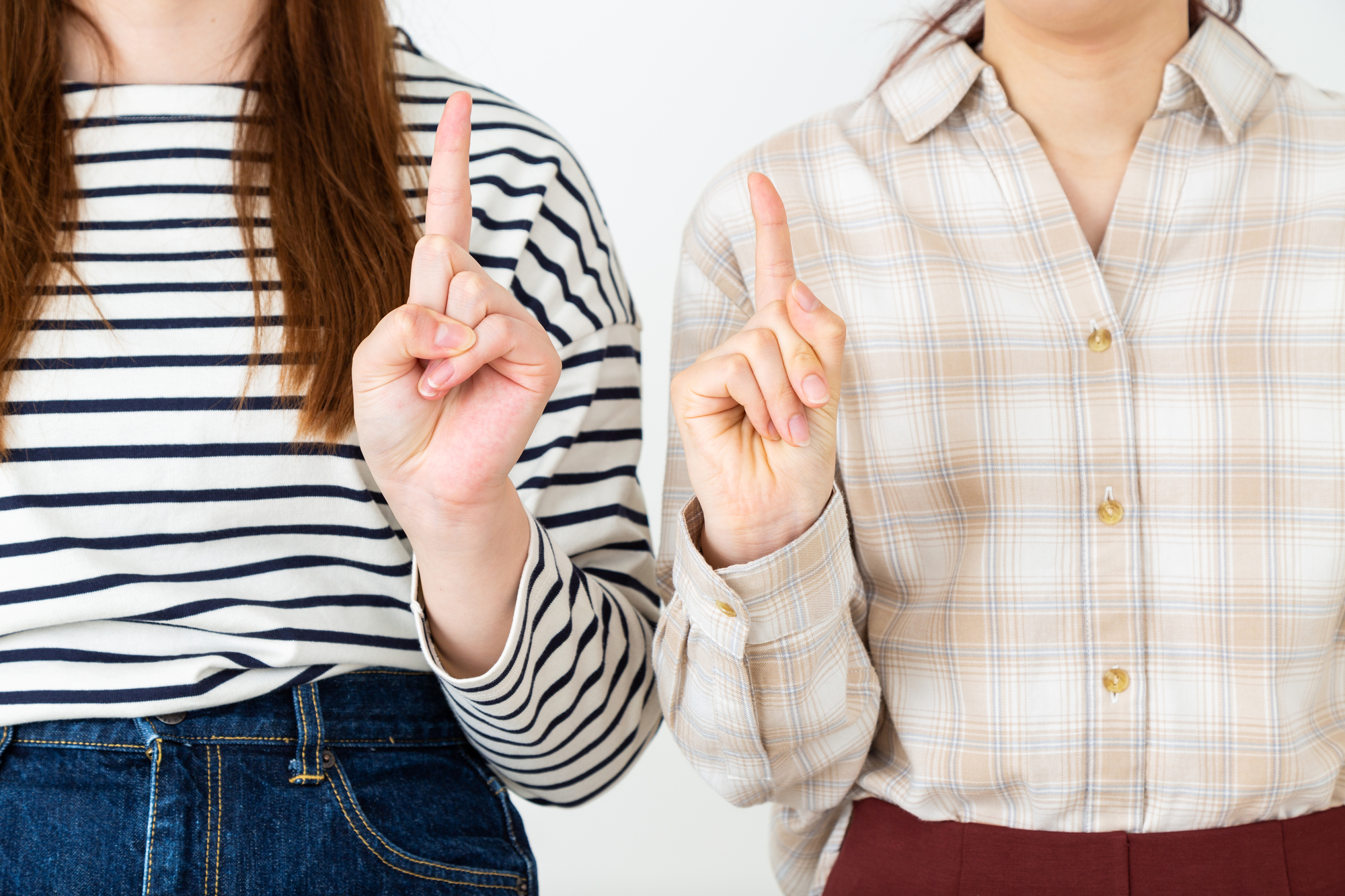 人差し指を立てる若い女性二人