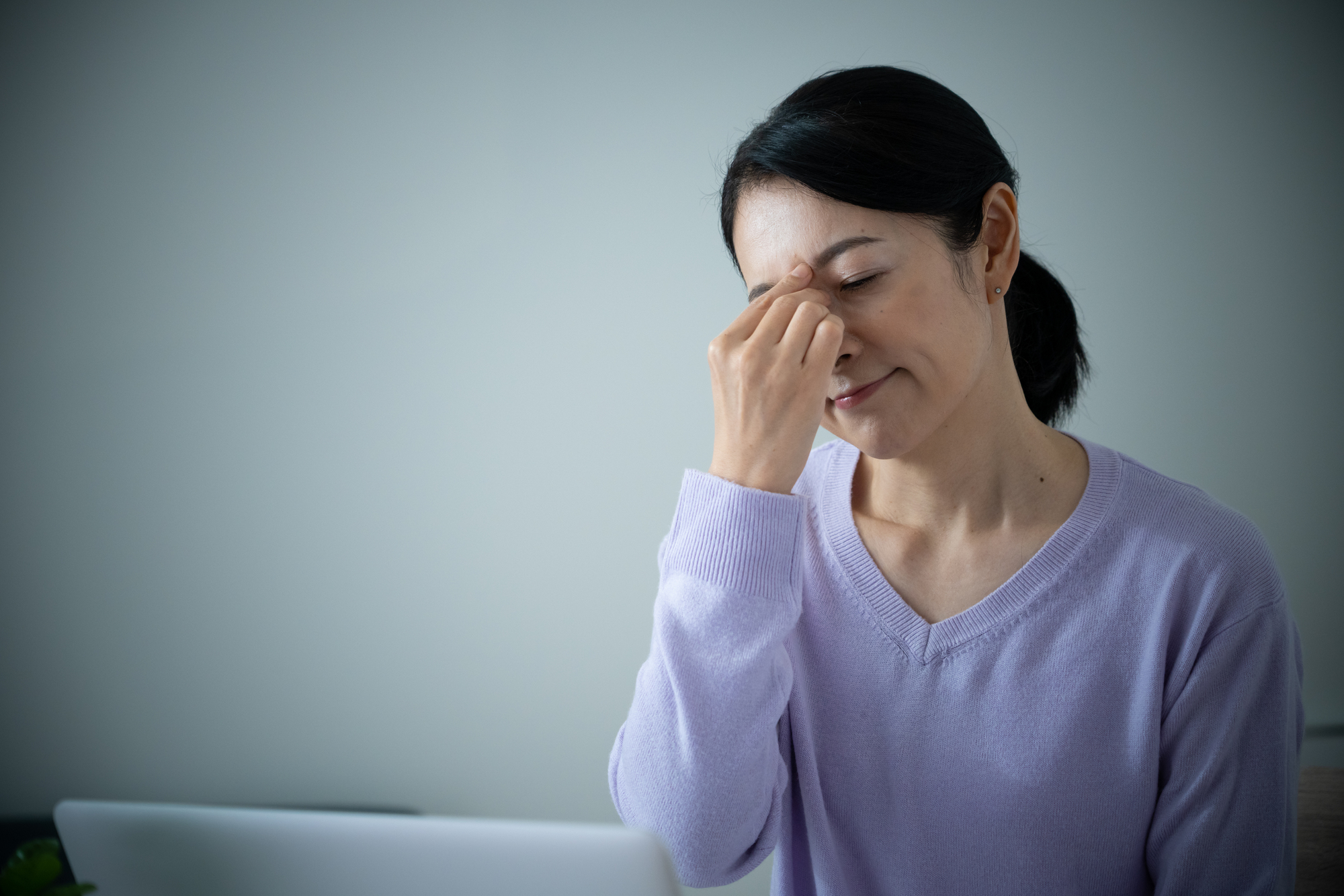 眉間を押さえる中年女性