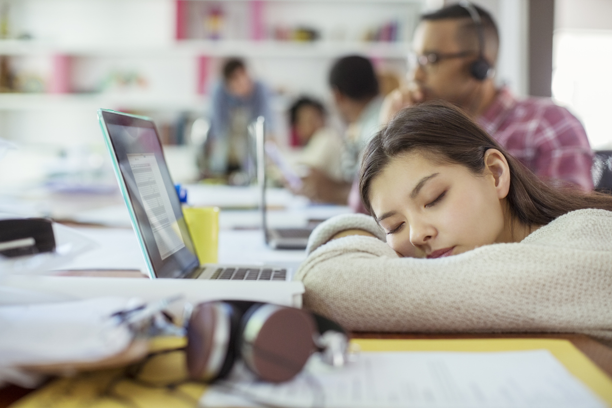 オフィスのデスクで仮眠をとる女性