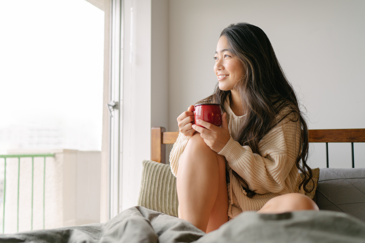 寝起きに暖かい飲み物を飲む女性