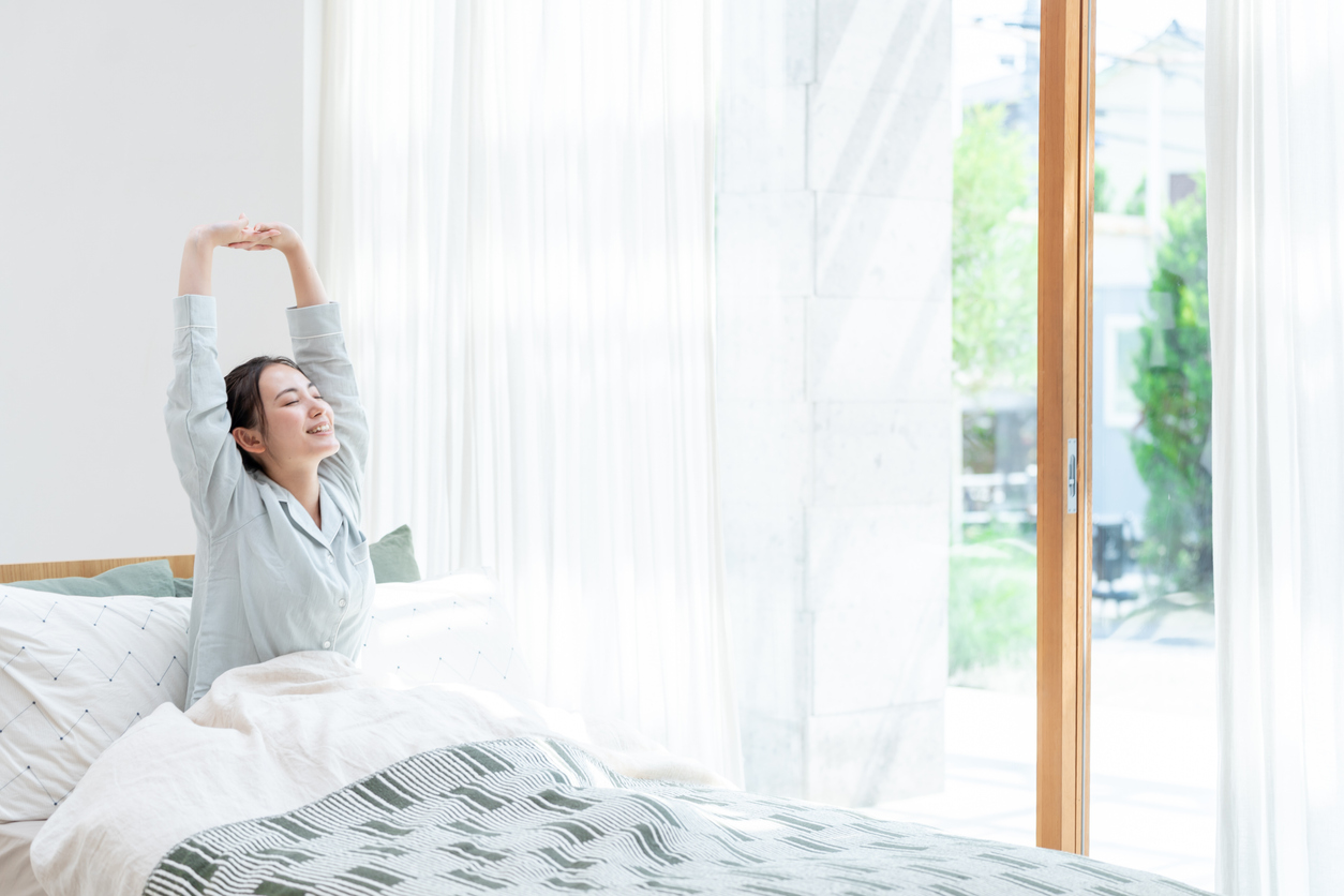 寝起きに伸びをする女性