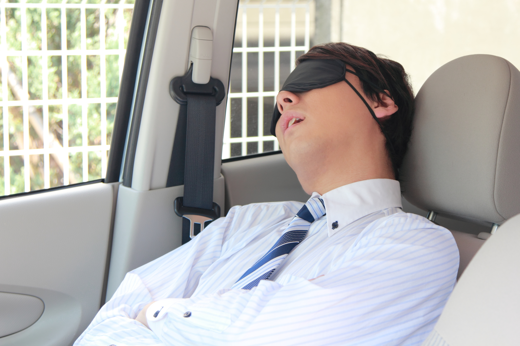 車の中でアイマスクを付けて寝るサラリーマン