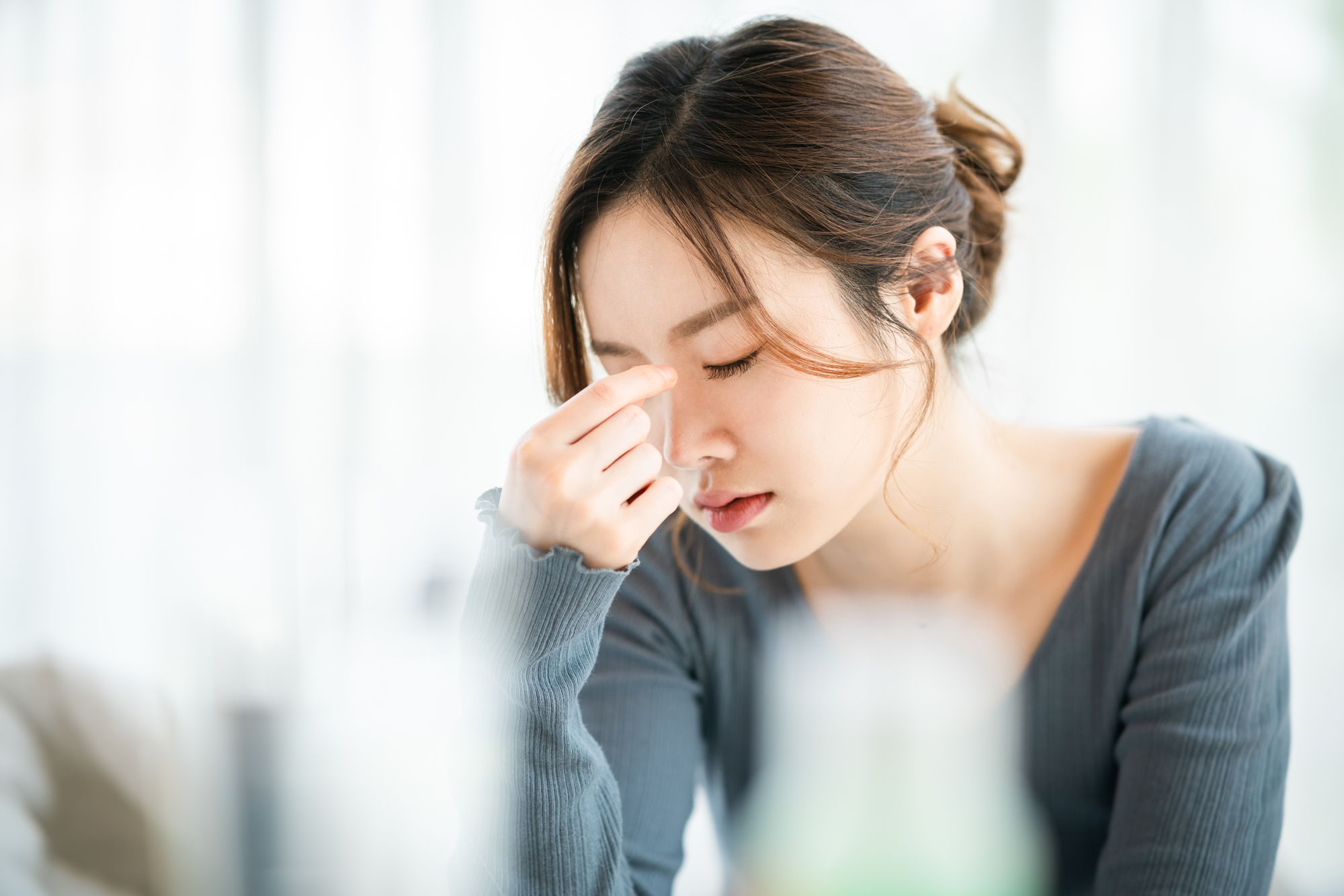 眉間を押さえる女性