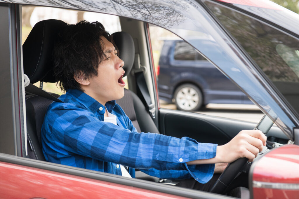 運転に疲れて欠伸をする日本人男性
