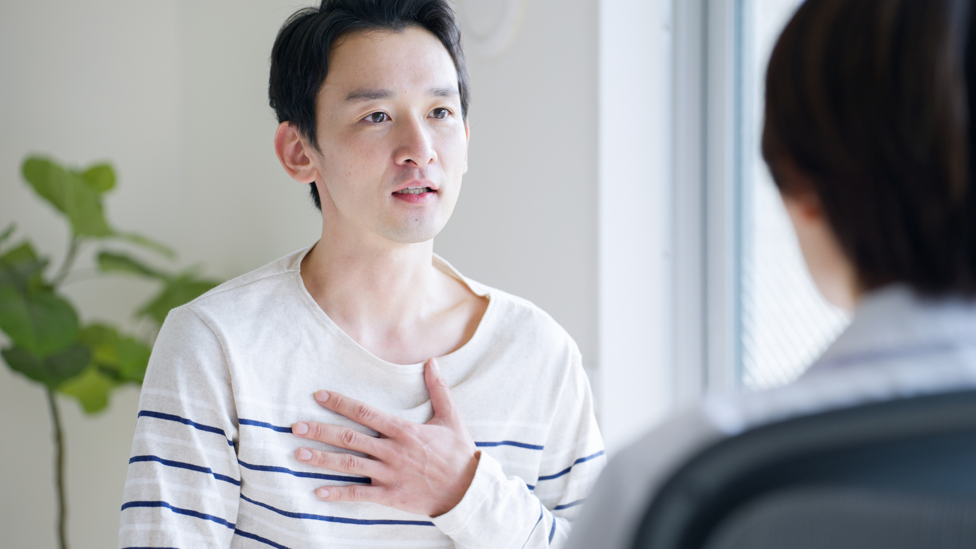 医師に症状を伝えている男性患者